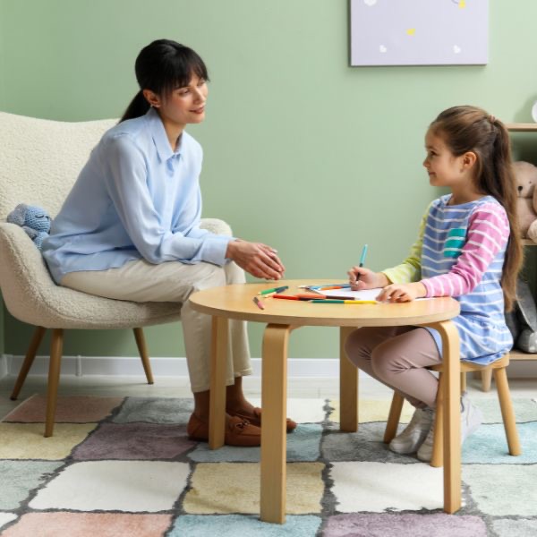 A therapist and a young girl working together at a small table