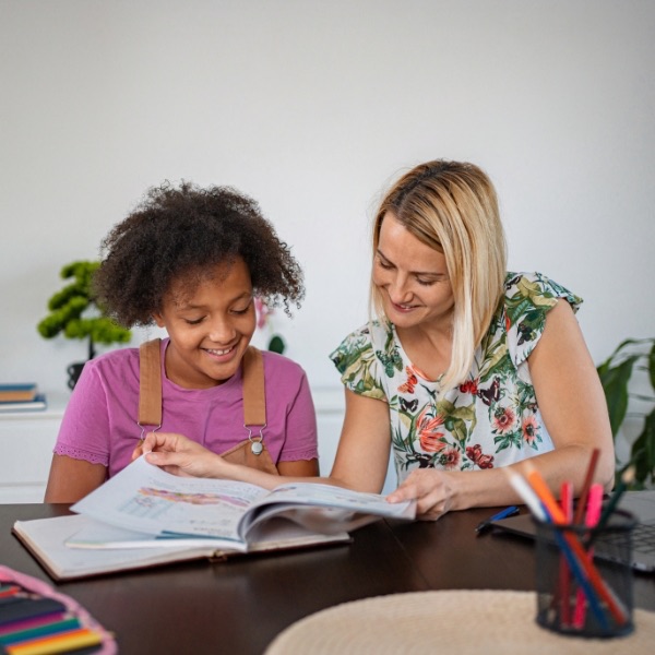A tutor and a young girl reading a workbook together